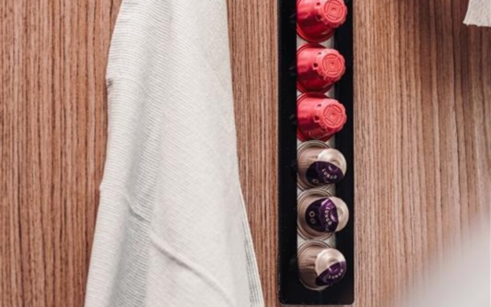 Wall mount in the Carado motorhome with a towel, kitchen roll and coffee capsules on a wooden panel
