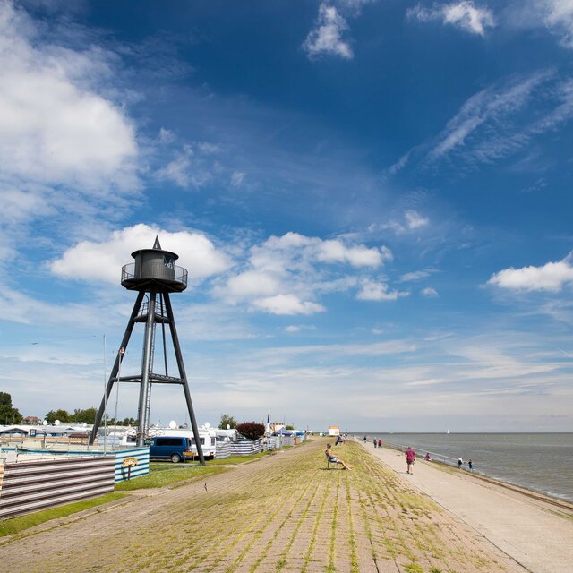 Seaside campsite by the dike with viewing tower, caravan and coastal path