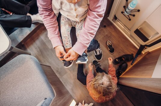 Espace d’entrée du camping-car Carado, avec des adultes et des enfants en train d’enfiler leurs chaussures