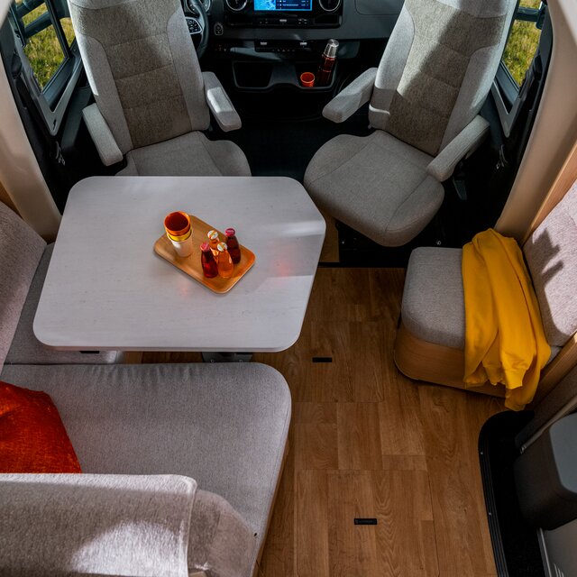 Seating, covered with a yellow blanket next to the entrance door with integrated rubbish bin in the HYMER MasterLine