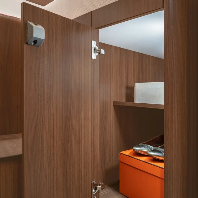 Open wardrobe with shelves filled with an orange box and silver-colored ballerinas in the HYMER B-ML T