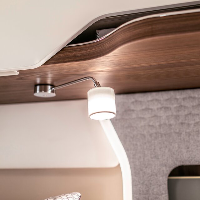 Reading lamp with silver arm and white shade in the bed area of the HYMER B-Class MasterLine I motorhome
