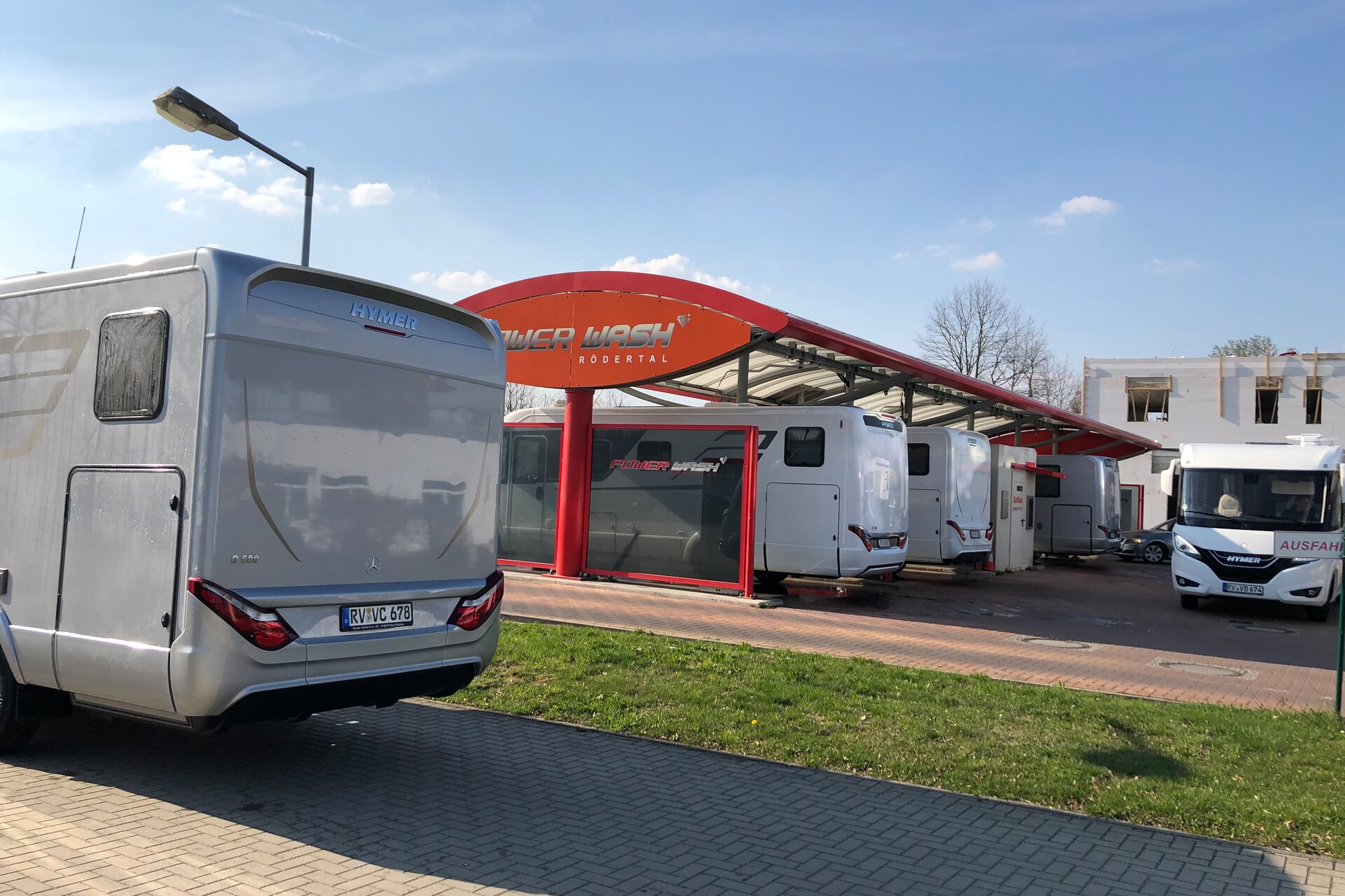 Hymer motorhome in front of a carwash that is filled with other motorhomes