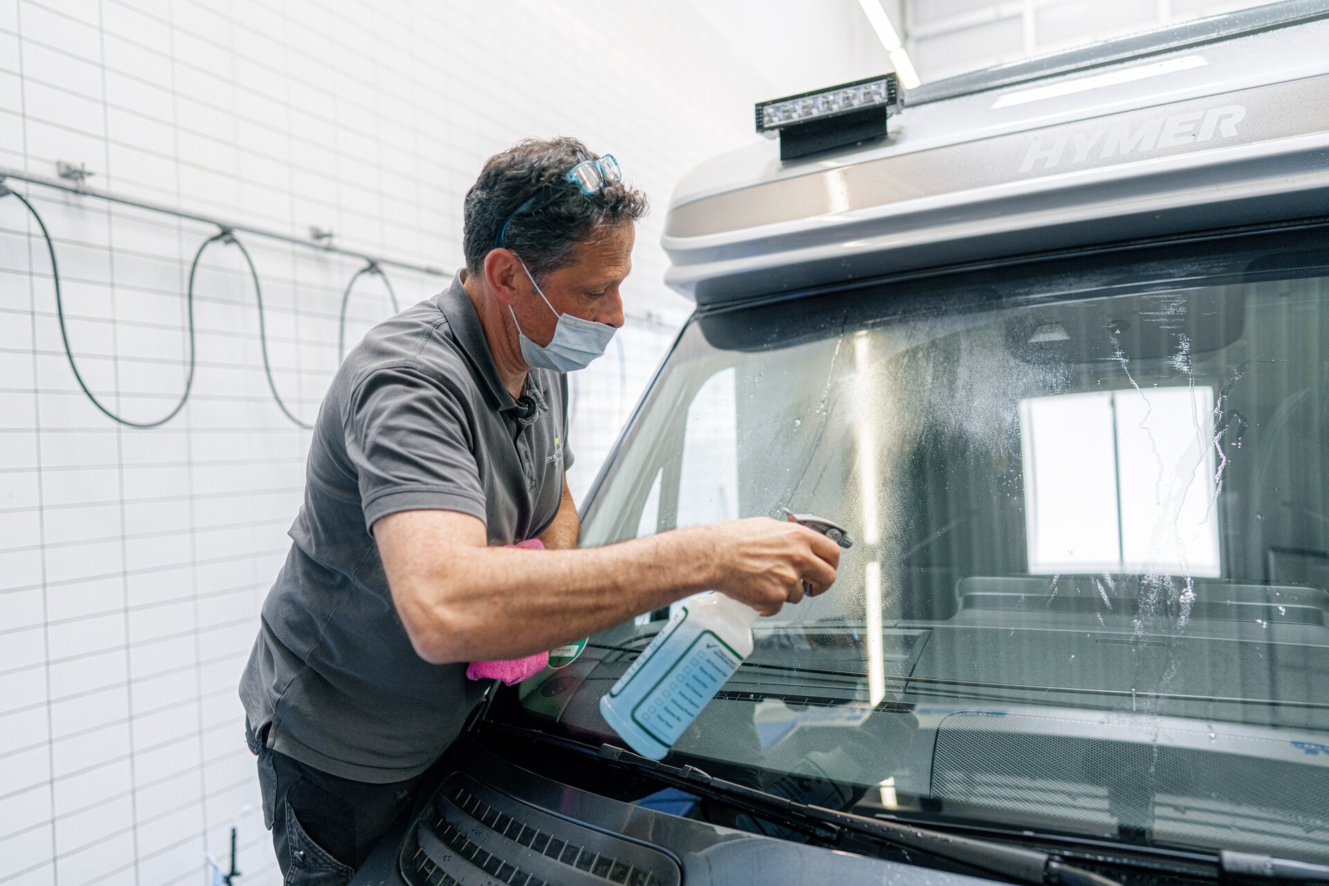 Manual cleaning of the outside of the HYMER motorhome windscreen with a special cleaning product