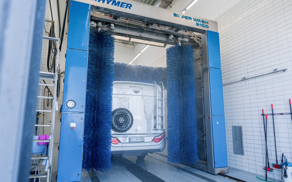 Rear view of the HYMER motorhome standing in the wash hall with a spare wheel on the back at the drying rag system