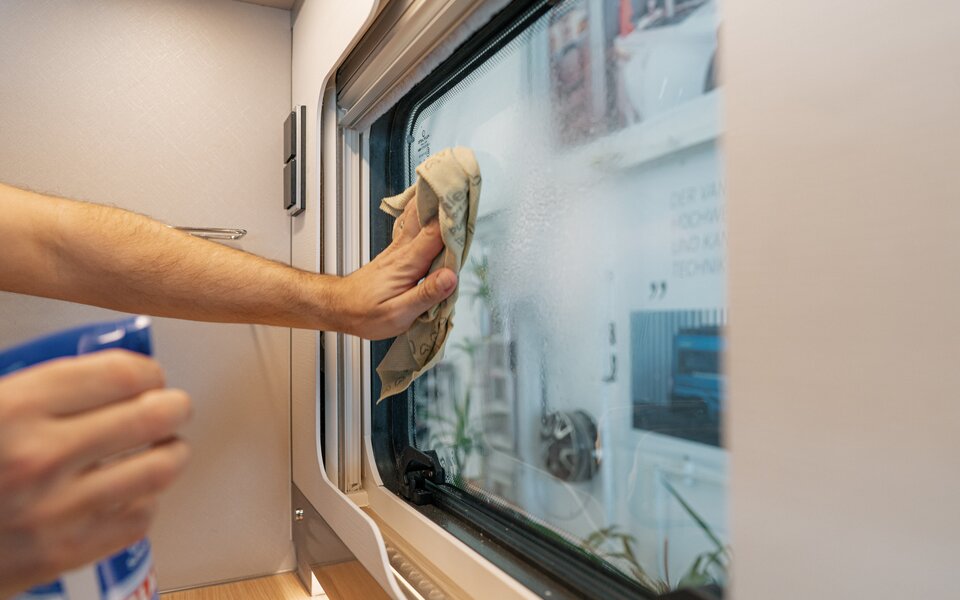 Manual interior cleaning of the side windows in the HYMER motorhome with a special cleaning product
